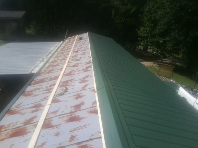 Old rusted panels beside newly installed green metal roofing — Wind Damage Roof Repair by Roofing Brothers in Kewanna