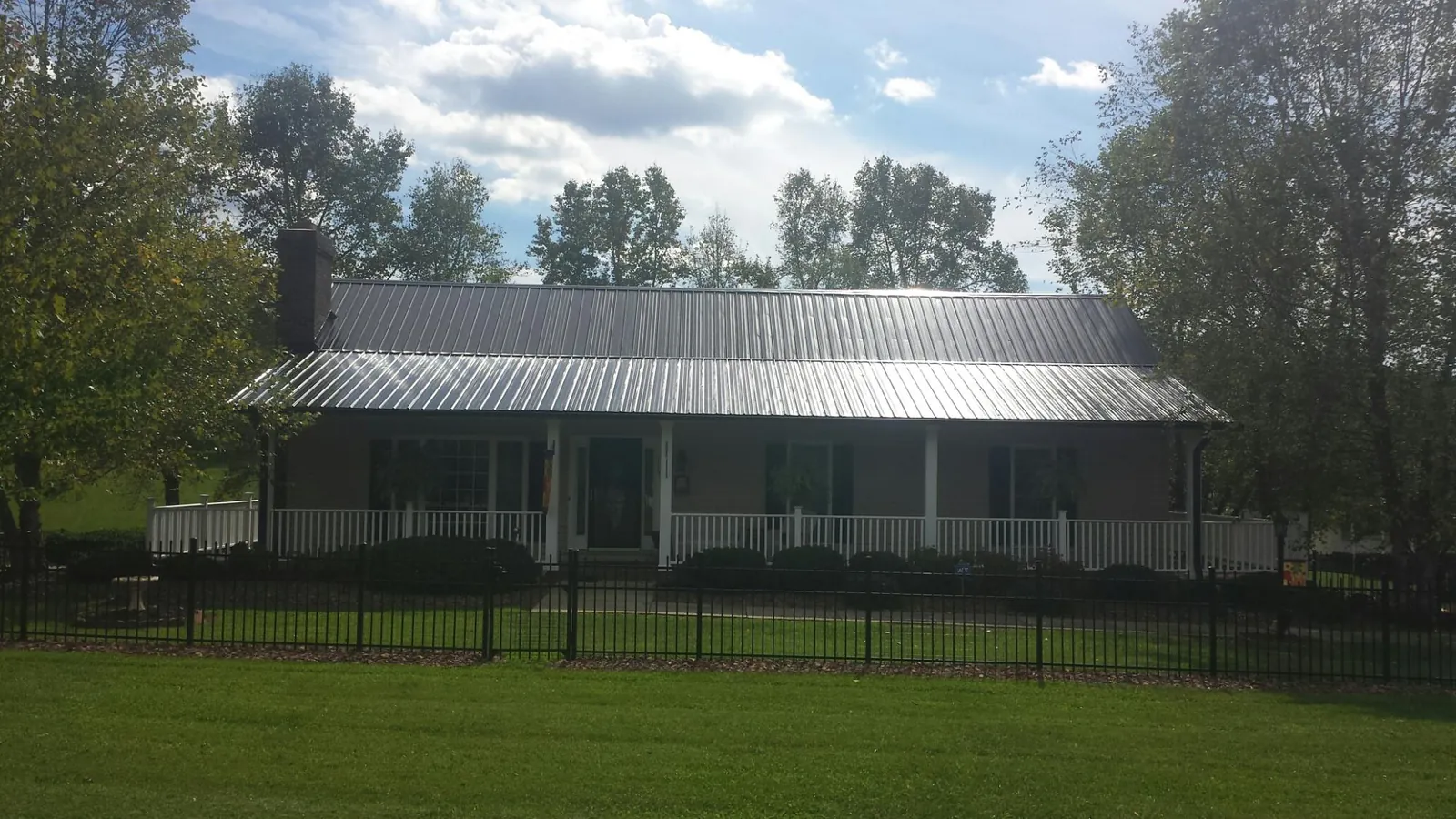Gray metal roof on a brick ranch with a full width front porch — Gutter Guard Installation work by our crew in Kewanna