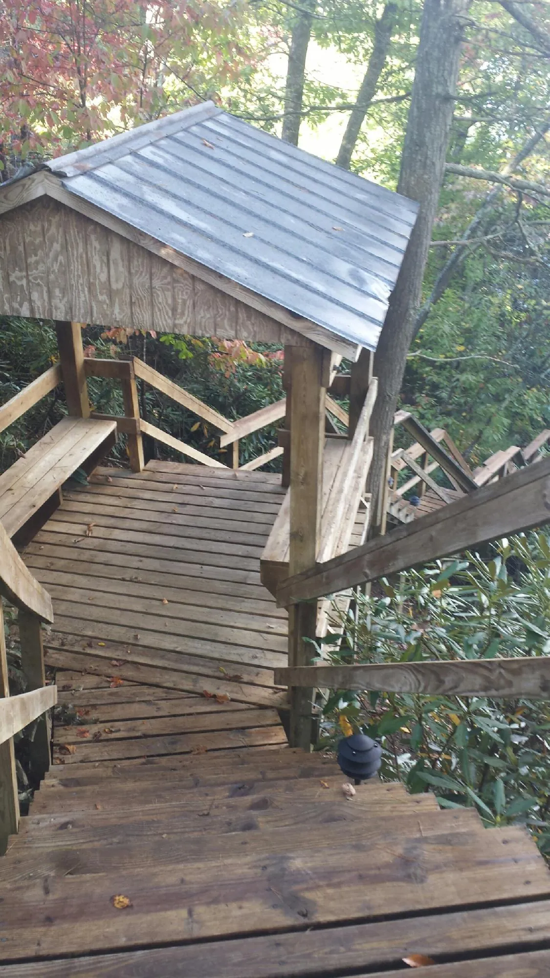 Metal roofed shelter over wooden steps on a wooded walkway — Skylight Repair & Installation work by our crew in Kewanna