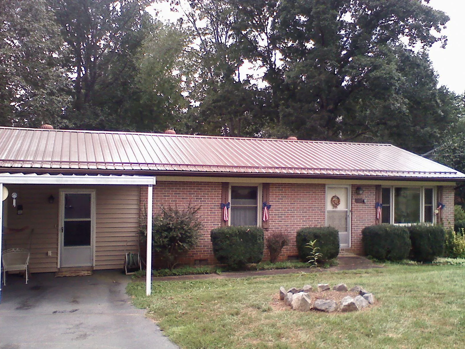 Bronze metal roof and carport on a brick ranch home — Roof Repair work by our crew in Kewanna