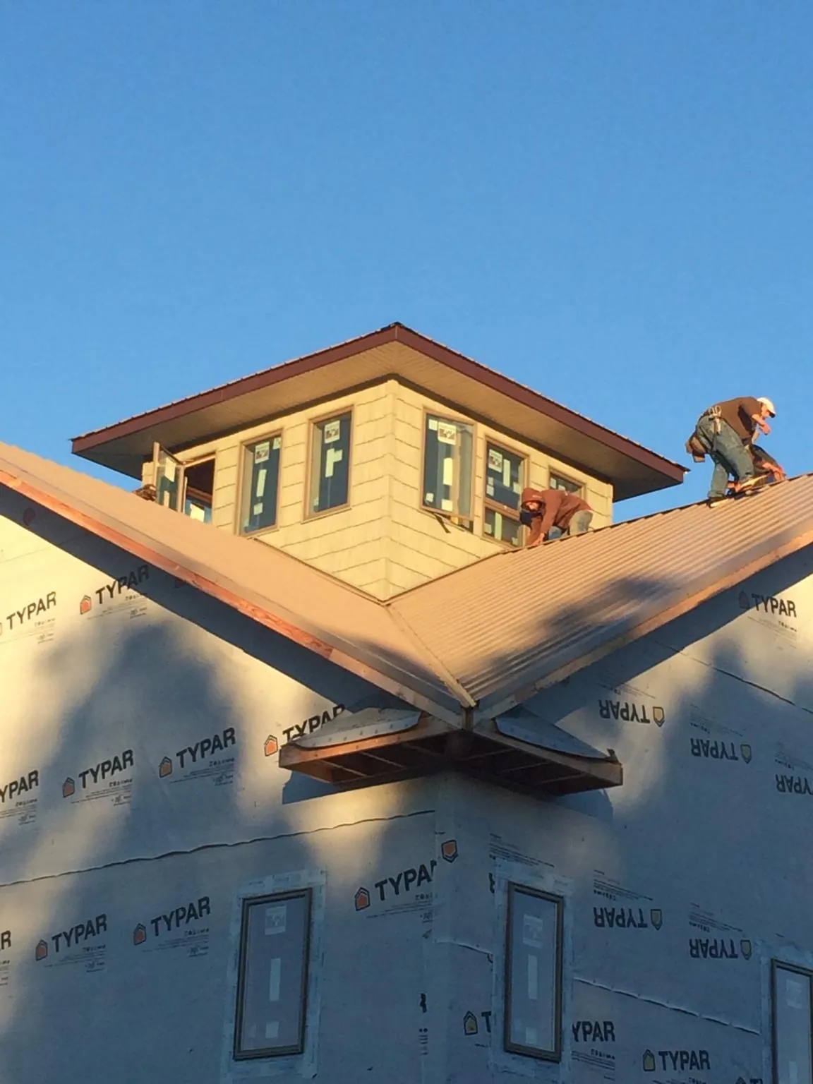 Roofers working around a rooftop cupola on a new metal roof at sunset — Roof Waterproofing in Kewanna by Roofing Brothers
